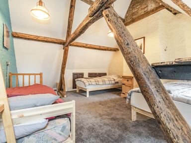 A bedroom with three beds wooden beams and a nightstand at 48 High Street in Bridlington