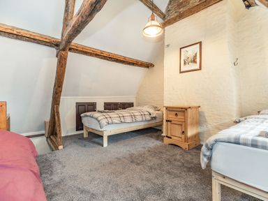 A bedroom with exposed wooden beams two single beds a wooden nightstand and a hanging light at 48 High Street in Bridlington