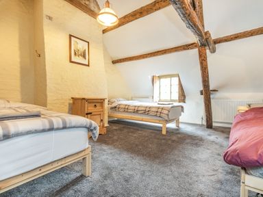A bedroom with three single beds a wooden nightstand exposed wooden beams and a small window at 48 High Street in Bridlington