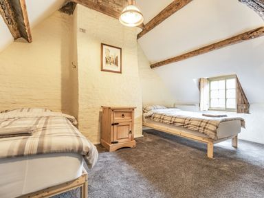 A bedroom with two single beds a wooden nightstand and a window at 48 High Street in Bridlington