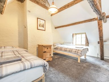 A bedroom with two single beds a wooden nightstand and exposed wooden beams at 48 High Street in Bridlington