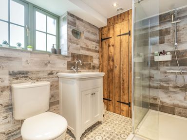 A bathroom with a toilet sink vanity wooden door and glass shower at 48 High Street in Bridlington