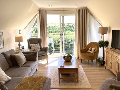 A living room with a sofa, armchair, and coffee table at Larchwood Lodge in Ellon