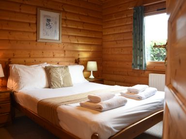A bedroom with a wooden bed with white linens and towels on a bed at Hillside View in Rhayader