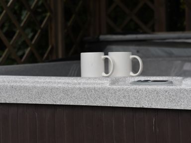 Two white mugs on the edge of a hot tub with a control panel nearby at Hillside View in Rhayader