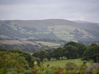 A countryside landscape with rolling hills trees and fields at Hillside View in Rhayader