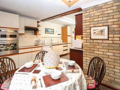 A kitchen with a dining table set for four and wooden chairs at Walnut Tree Cottage in Catfield