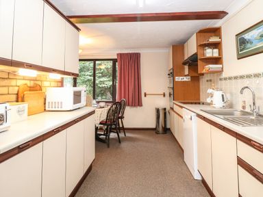 A kitchen with countertops cabinets a sink microwave toaster dining table and chairs at Walnut Tree Cottage in Catfield