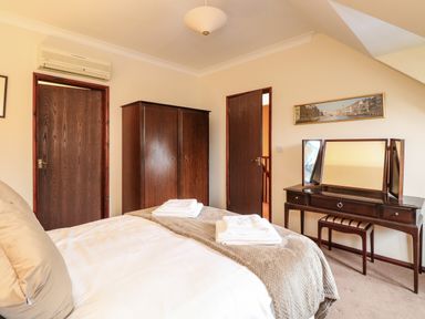 A bedroom with a bed folded towels a wardrobe and a dressing table with a mirror at Walnut Tree Cottage in Catfield
