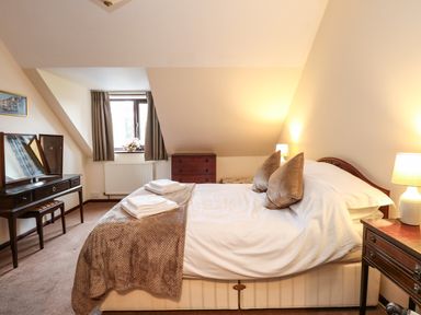 A bedroom with a double bed two bedside tables with lamps a wooden dresser and a dressing table with mirror at Walnut Tree Cottage in Catfield
