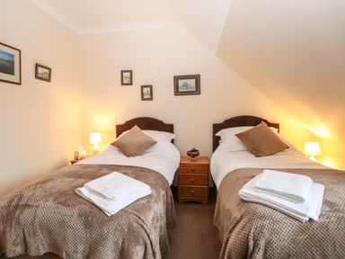 A bedroom with two single beds side by side with bedside table and lamps at Walnut Tree Cottage in Catfield