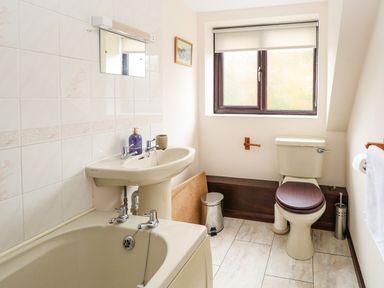 A bathroom with a bathtub sink and toilet near a window at Walnut Tree Cottage in Catfield