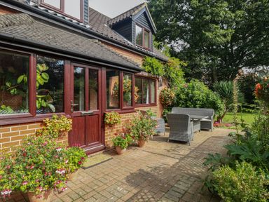 A patio with outdoor furniture and potted plants outside a brick house at Walnut Tree Cottage in Catfield