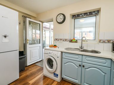 A kitchen with a refrigerator washing machine sink and a door leading outside at Kingfisher Cottage in Weymouth
