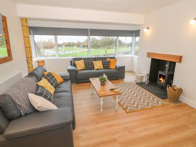 A living room with two sofas a wooden coffee table a fireplace and large windows at Berth in Afonwen near Criccieth