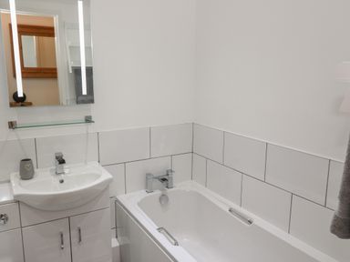 A bathroom with a sink a mirror and a bathtub with white tiles at Berth in Afonwen near Criccieth
