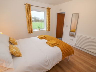 A bedroom with a double bed and yellow curtains at Berth in Afonwen near Criccieth