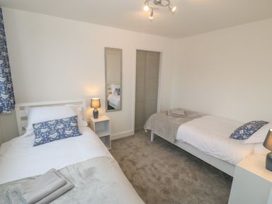 A bedroom with two single beds side tables with lamps a mirror and a closet at Berth in Afonwen near Criccieth