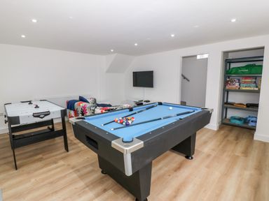 A game room with a pool table air hockey table colorful sofa tv and shelves with games at Berth in Afonwen near Criccieth
