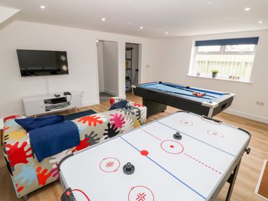 A game room with a colorful patterned couch a wall-mounted television an air hockey table and a pool table at Berth in Afonwen near Criccieth