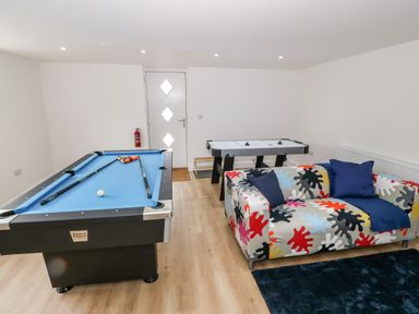 A game room with a pool table air hockey table and a patterned sofa at Berth in Afonwen near Criccieth