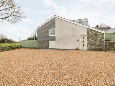 An exterior view of a house with a gravel driveway and a small potted plant by the door at Berth in Afonwen near Criccieth