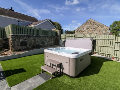 An outdoor hot tub on artificial grass with a small step and fenced yard at Berth in Afonwen near Criccieth