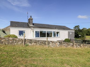 A single-story house with stone wall and grassy lawn at Berth in Afonwen near Criccieth