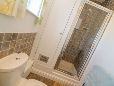 A bathroom with a toilet a tiled shower enclosure and a blue towel at Rospletha Bungalow in Treen