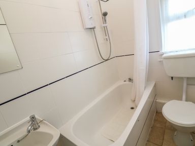 A bathroom with a bathtub and shower unit a toilet and a sink at Rospletha Bungalow in Treen
