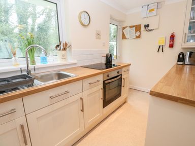 A kitchen with a sink, stovetop, oven, utensils, clock, and countertop appliances at 17 River Banks in Liskeard
