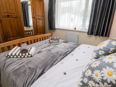 A bedroom with a wooden bed and wardrobe and gray blankets at 17 River Banks in Liskeard