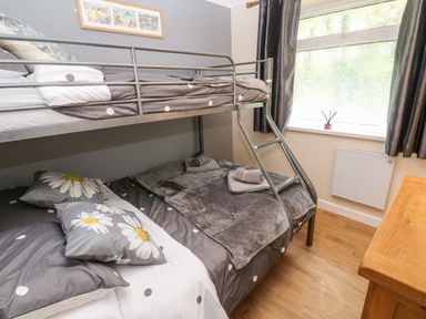 A bedroom with bunk beds dressed with grey polka dot and floral bedding next to a window at 17 River Banks in Liskeard