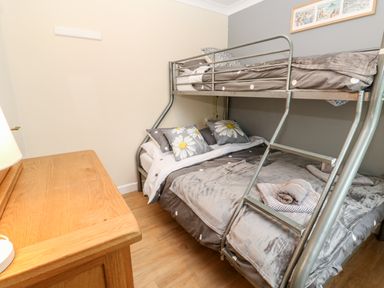 A bedroom with a metal bunk bed and a wooden dresser at 17 River Banks in Liskeard