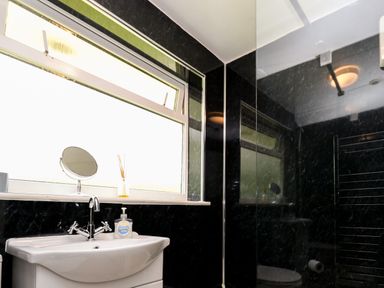 A bathroom with a white sink a faucet a mirror and a window at 17 River Banks in Liskeard
