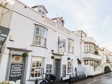 The exterior of the Ferry Boat Inn with windows and signage along a street at Teign Cottage in Shaldon