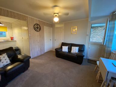 A living room with a sofa, armchair and clock at 246 California Road, California, Norfolk