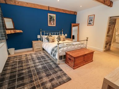 A bedroom with a double bed bedside tables and wooden chest at The Old Workshop Middleton near Belford