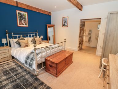 A bedroom with a double bed a wooden chest at the foot of the bed and an adjacent bathroom at The Old Workshop in Middleton near Belford