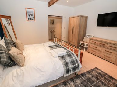 A bedroom with a bed mirror wardrobe dresser chair and television at The Old Workshop in Middleton near Belford
