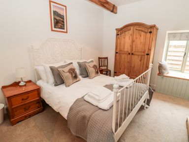 A bedroom with a double bed white metal frame wooden wardrobe bedside table and window seat at The Old Workshop in Middleton near Belford