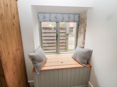 A window seat with wooden top cushions and a roller blind at The Old Workshop in Middleton near Belford
