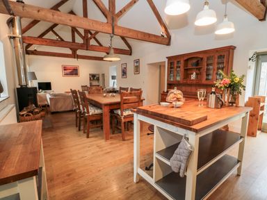 An open dining and living area with wooden beams wooden furniture and a kitchen island at The Old Workshop in Middleton near Belford
