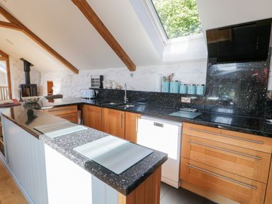 A kitchen with wooden cabinets black countertops and a skylight window at Tyn Llwyn in Pencoed near Corwen