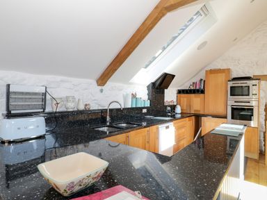 A kitchen with black countertops wooden cabinets and skylight window at Tyn Llwyn in Pencoed near Corwen