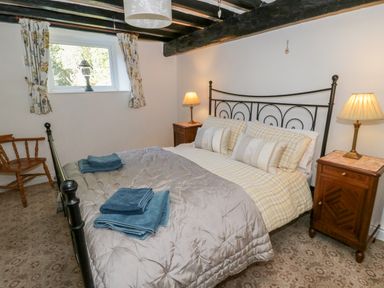 A bedroom with a metal bed frame and bedside tables with lamps at Tyn Llwyn Pencoed near Corwen