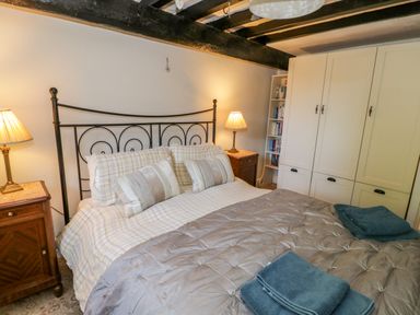 A bedroom with a double bed nightstands lamps and a wardrobe at Tyn Llwyn in Pencoed near Corwen