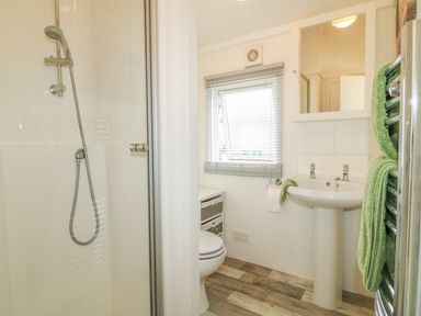 A bathroom with a shower enclosure sink toilet window and green towels at Smugglers Shack in Polperro