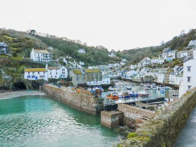 A harbor with boats docked surrounded by houses on hills at Smugglers Shack in Polperro