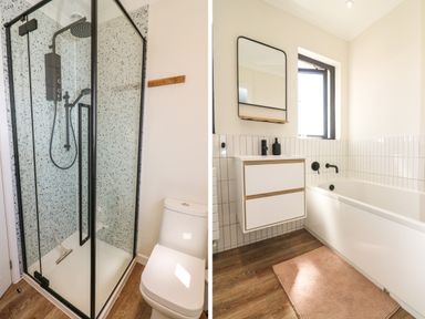 A bathroom with a glass shower enclosure and toilet beside it and a separate area with a bathtub a wall-mounted sink and mirror at Auverne Poundstock near Widemouth Bay
